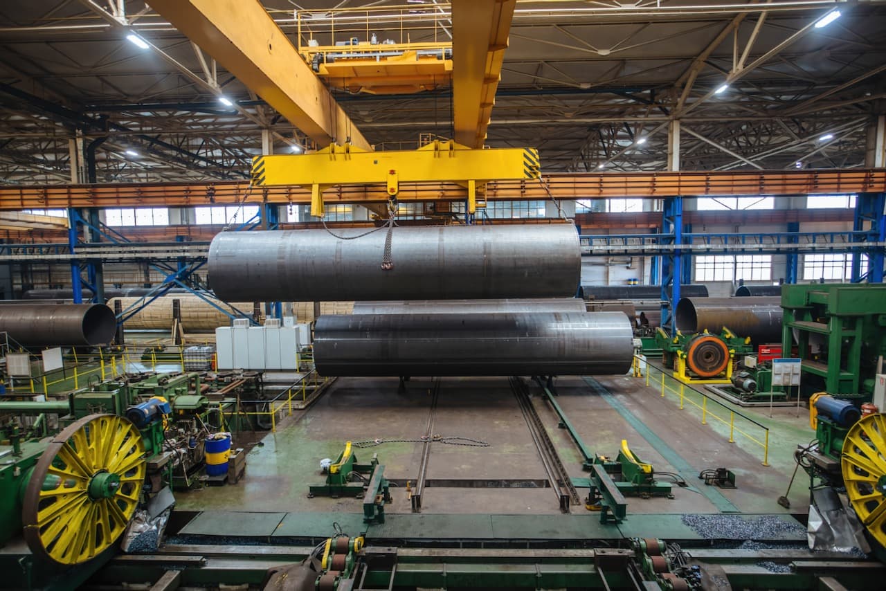 Máquinaria cargando un gran tubo de acero al carbón